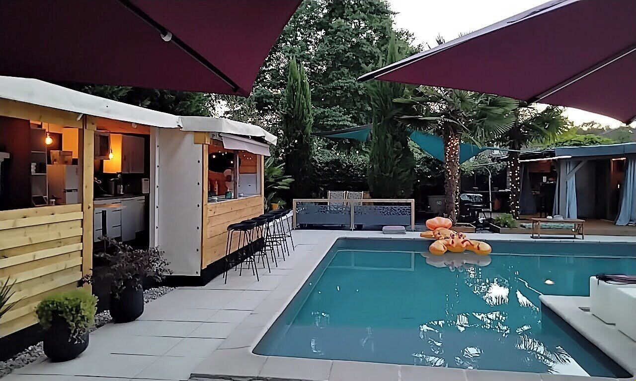 A pool area with a bar, outdoor seating, and a covered patio.