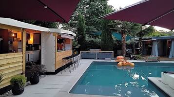 A pool area with a bar, outdoor seating, and a covered patio.