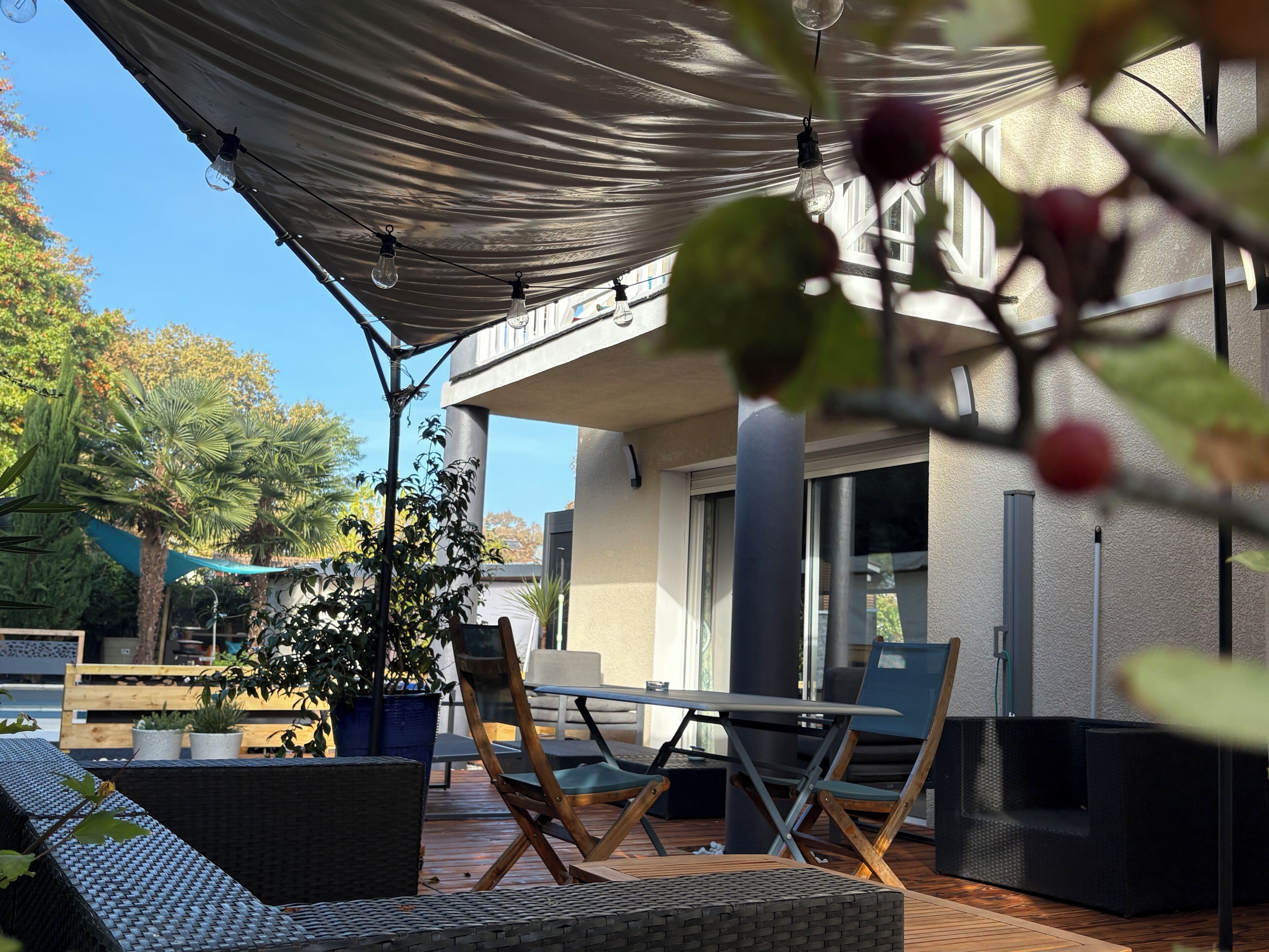 An outdoor patio with a table and chairs, a pergola, and potted plants.