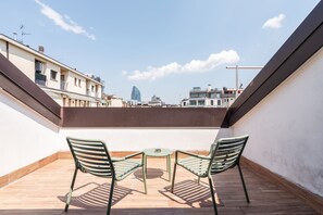 A rooftop terrace with two green chairs and a small table, overlooking a cityscape with modern buildings. - easyhomes - Brera Luxury Suites (Milan)