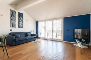 A spacious living room with a blue sofa, a glass coffee table, and a flat-screen TV. - easyhomes - Brera Luxury Suites (Milan)