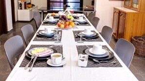 Une table à manger dressée avec des assiettes, des couverts et un plateau de fruits.