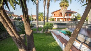 Un quartier résidentiel doté d’une piscine, de palmiers et d’une maison avec un toit rouge.