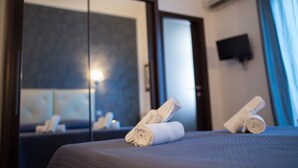 Une chambre d’hôtel avec un lit, un miroir et un téléviseur fixé au mur.