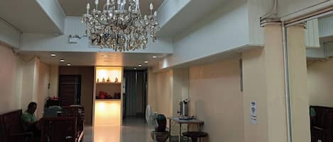 A spacious lobby with a chandelier, a reception desk, and a seating area.