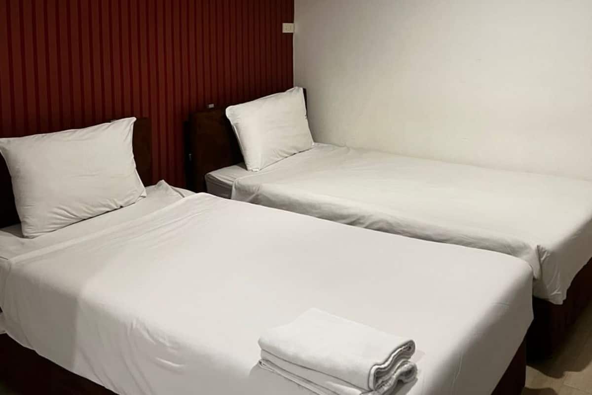 Habitación de hotel con dos camas individuales, aire acondicionado de pared y un techo blanco liso.