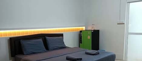 Ein Schlafzimmer mit einem Bett, einem Kopfteil mit integrierter Beleuchtung, einer Klimaanlage und einem grünen Schrank.