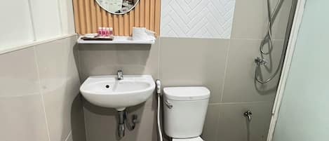 Un baño con lavamanos, inodoro, espejo y ducha.