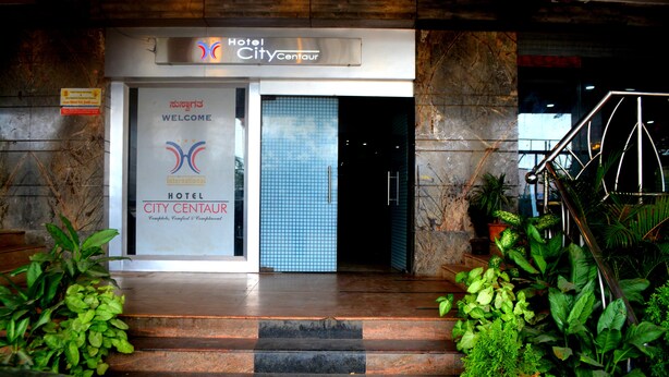 The entrance of Hotel City Centaur with a signboard, a tiled wall, and a staircase leading inside. - Hotel City Centaur (Bengaluru)