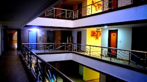 A multi-level interior with a balcony, a staircase, and a door with a light switch. - Hotel City Centaur (Bengaluru)