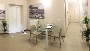 Een restaurantgedeelte van een hotel met een glazen tafel, stoelen en potplanten.