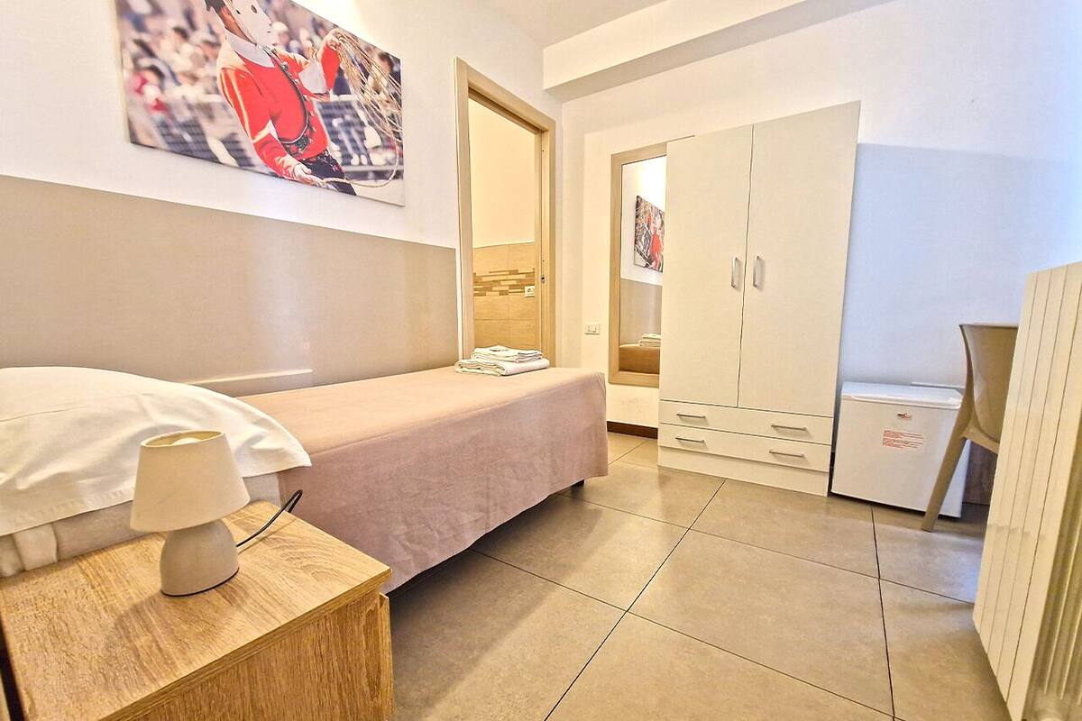 A bedroom with a bed, bedside table, lamp, and a wardrobe.