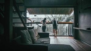 A modern interior with a staircase, a sofa, and a balcony with a view of palm trees. - Cloudy Hostel (Bangkok)