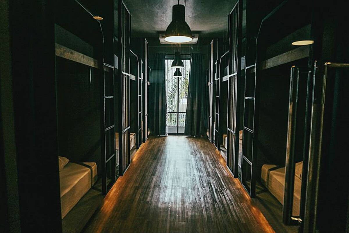 A narrow hallway with wooden flooring and a large window at the end.