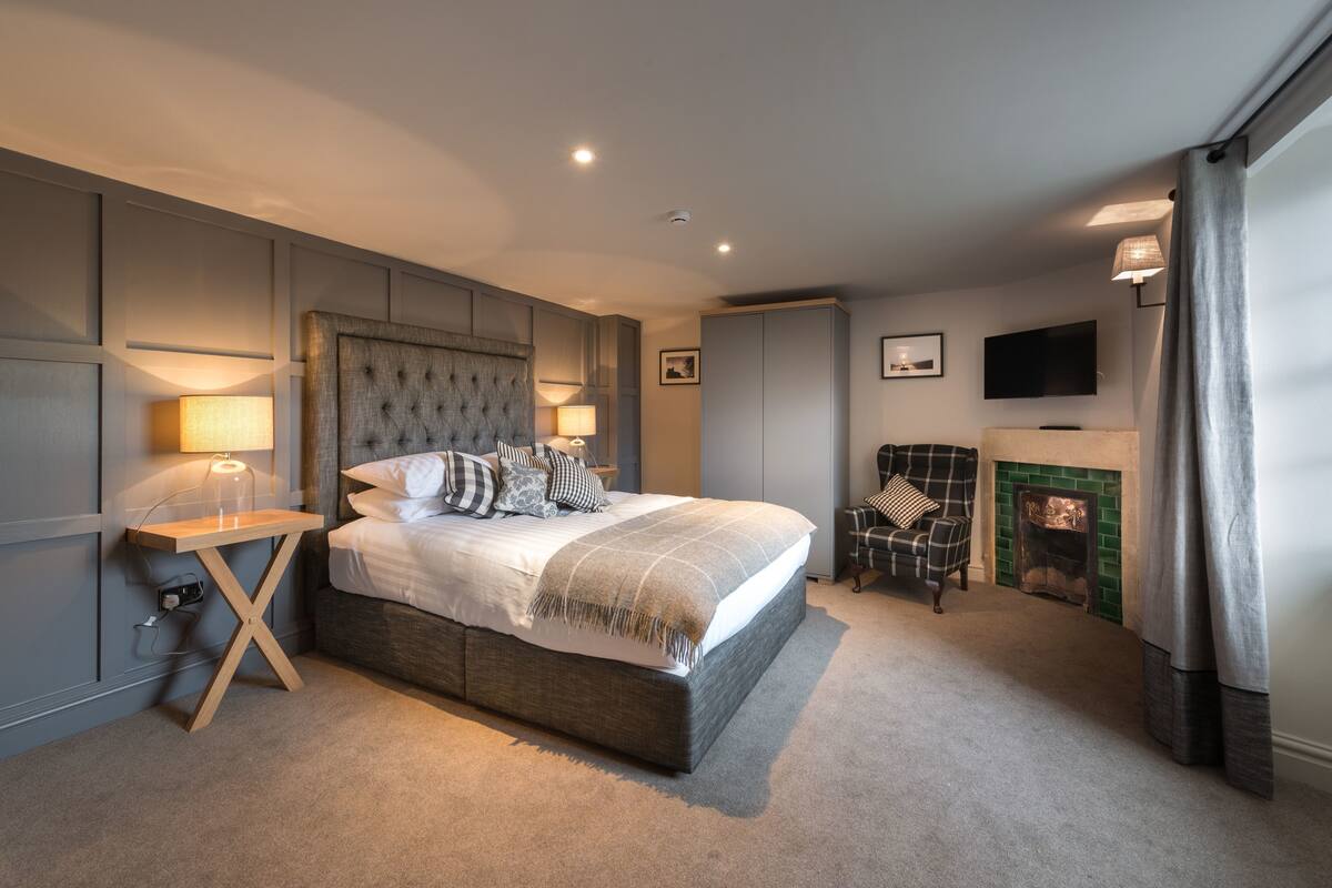 Um quarto moderno com uma cama grande, abajures, uma televisão e uma lareira.