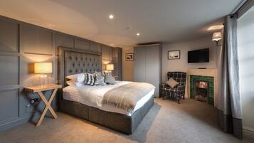 A modern bedroom with a large bed, bedside lamps, a television, and a fireplace.