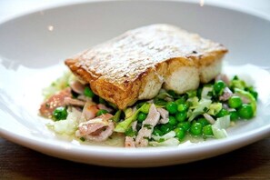 A dish with a piece of bread on top, surrounded by green peas and other vegetables.