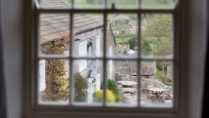 A window with a view of a rural village, including houses and a church. - Assheton Arms (Clitheroe)