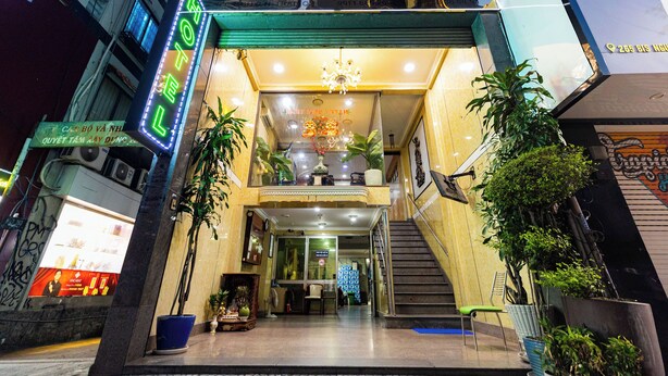 The entrance of HANI PHUOC HOTEL with a staircase leading up to the lobby, potted plants, and a chandelier.