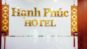 A hotel sign with the name "Hanh Phuc Hotel" in gold letters on a white marble background.
