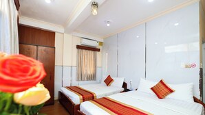 A hotel room with two beds, wooden flooring, a large mirror, and a wooden wardrobe.