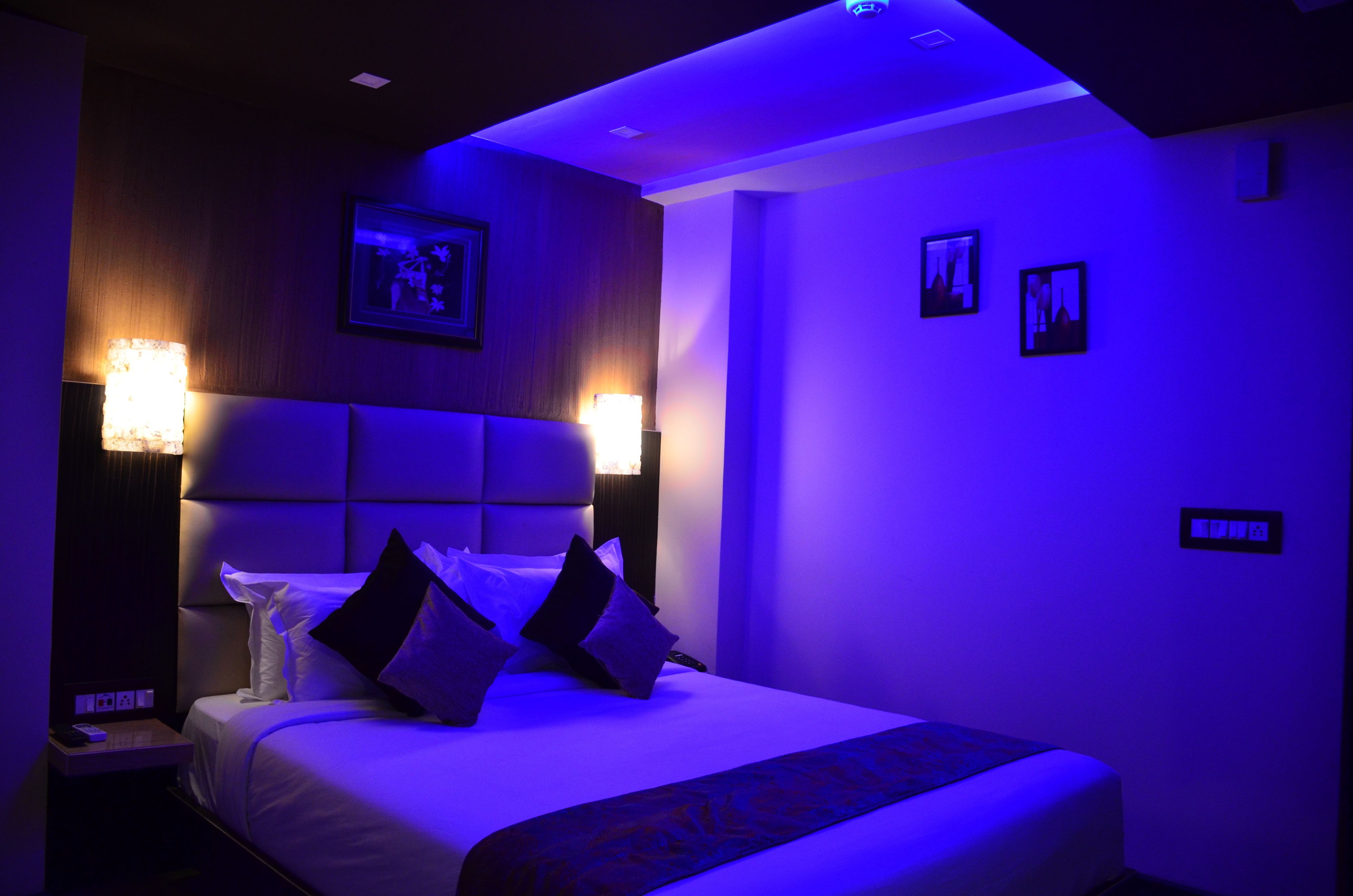 A hotel room with a large bed, two bedside lamps, a framed picture on the wall, and a small table with a lamp.