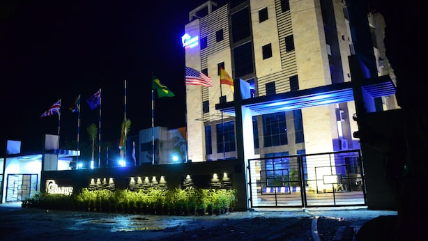 Un hotel con varias banderas, incluyendo la bandera estadounidense, y señalización iluminada.