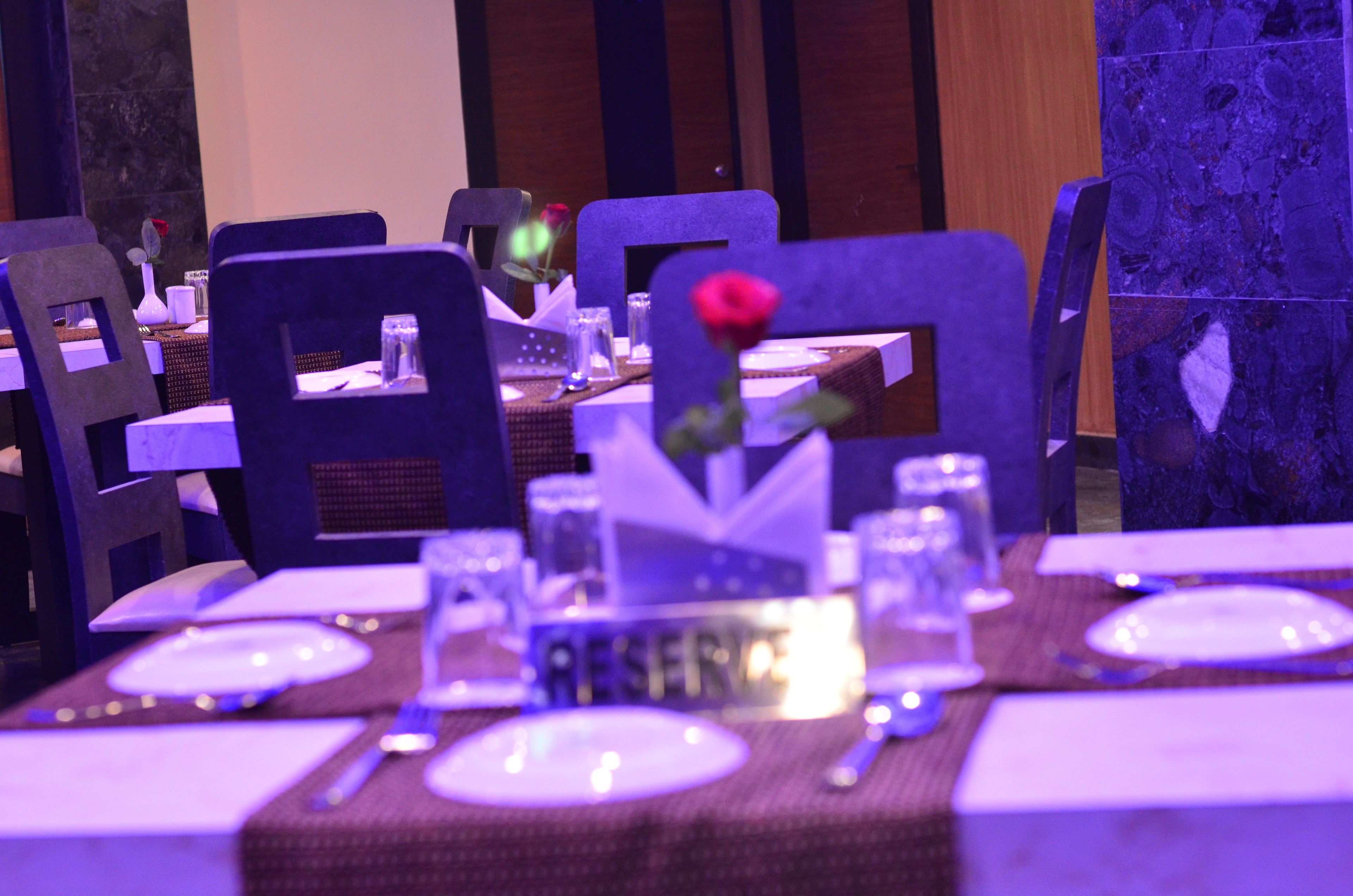 A dining table set with plates, cutlery, and a centerpiece with a rose.