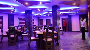 Un restaurante con mesas y sillas, un camarero y una persona con uniforme rojo.