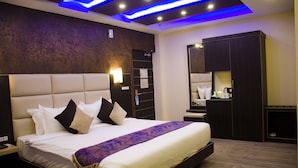 Una habitación de hotel moderna con una cama grande, un armario empotrado e iluminación azul en el techo.