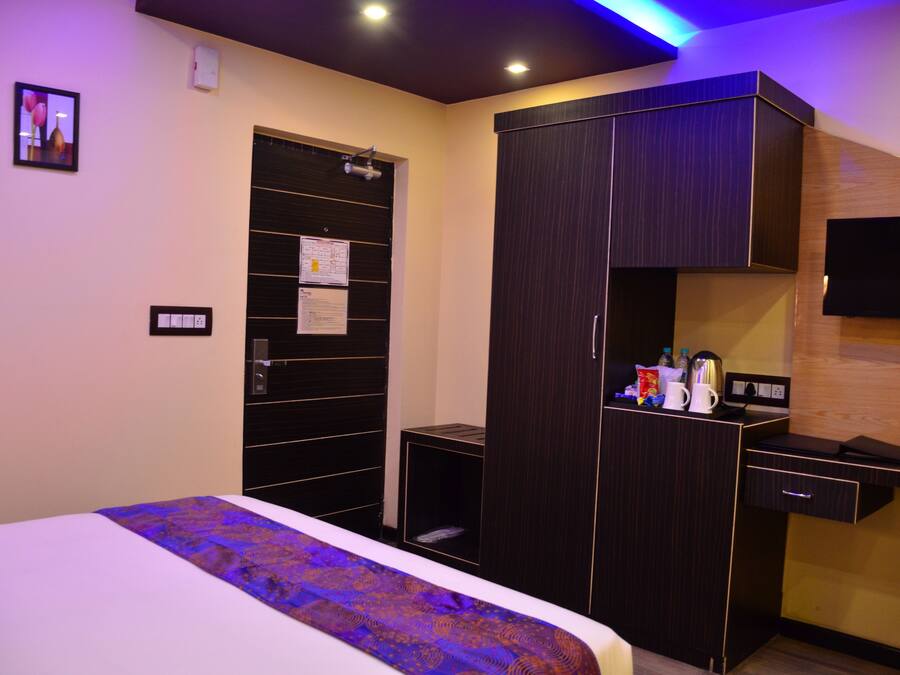 Habitación de hotel con cama, armario, escritorio y televisor de pantalla plana.