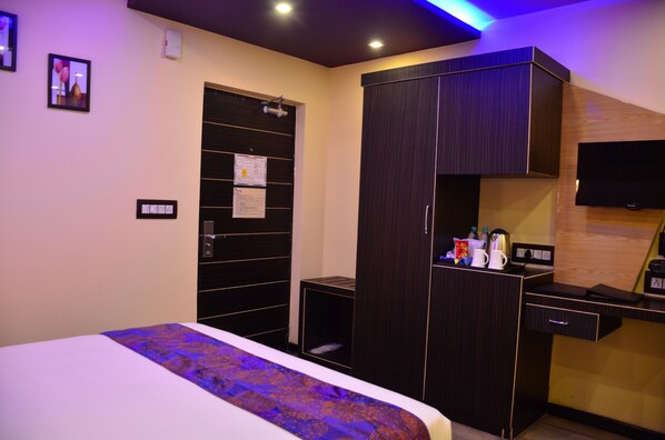 Enjoy a comfortable stay in this stylish room featuring a large bed, dark wood wardrobe, and flat-screen TV.