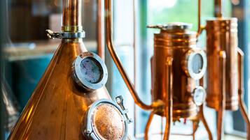 Un aparato de destilación de cobre con forma cónica y dos indicadores circulares, probablemente utilizado para medir presión o temperatura.