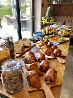 A breakfast buffet with croissants, bread, and fruit. - Forest (Burnley)