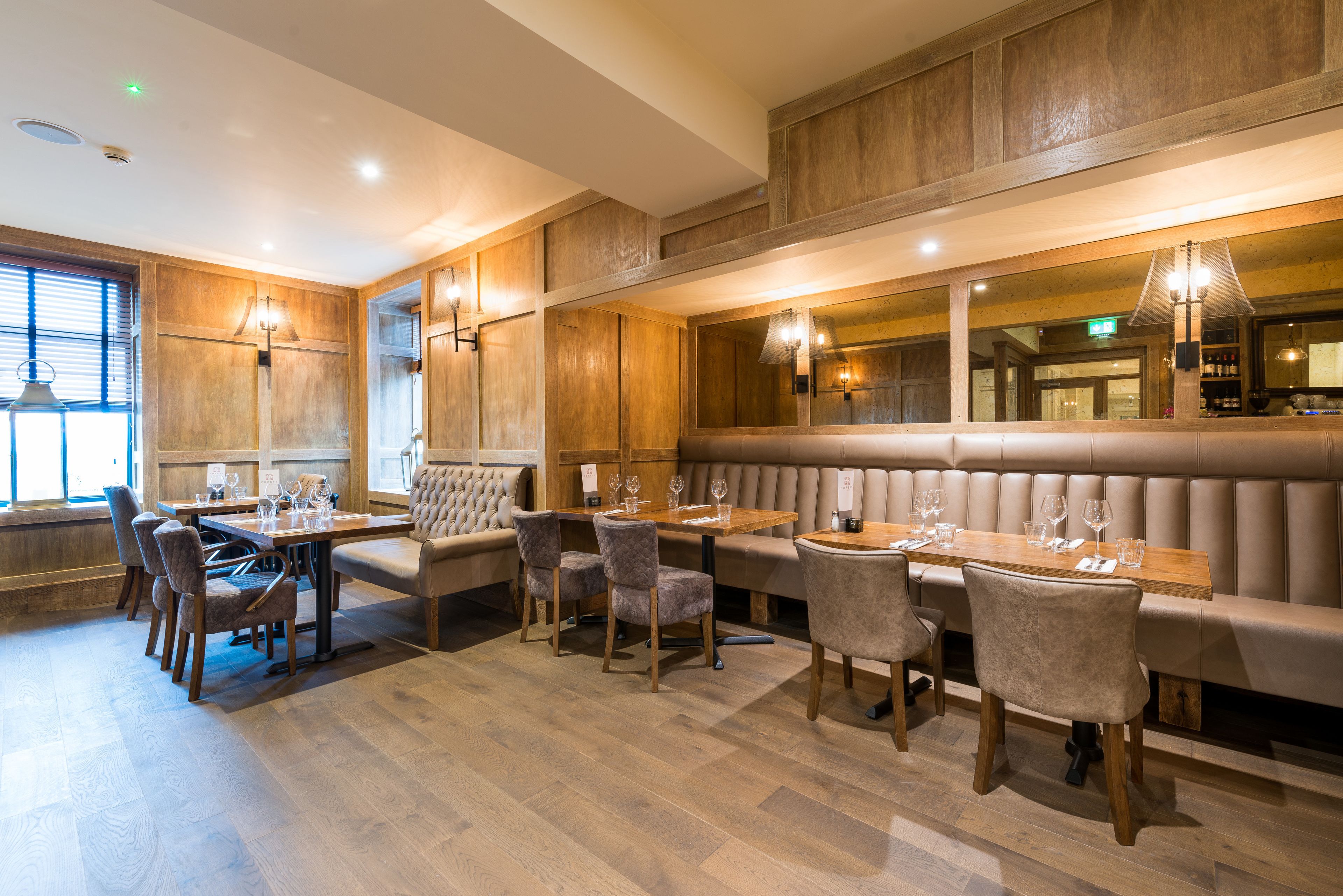 Een restaurant met houten paneelwanden, een lange toonbank en beklede zitplaatsen.