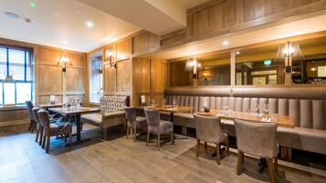 A restaurant with wooden panel walls, a long counter, and cushioned seating.