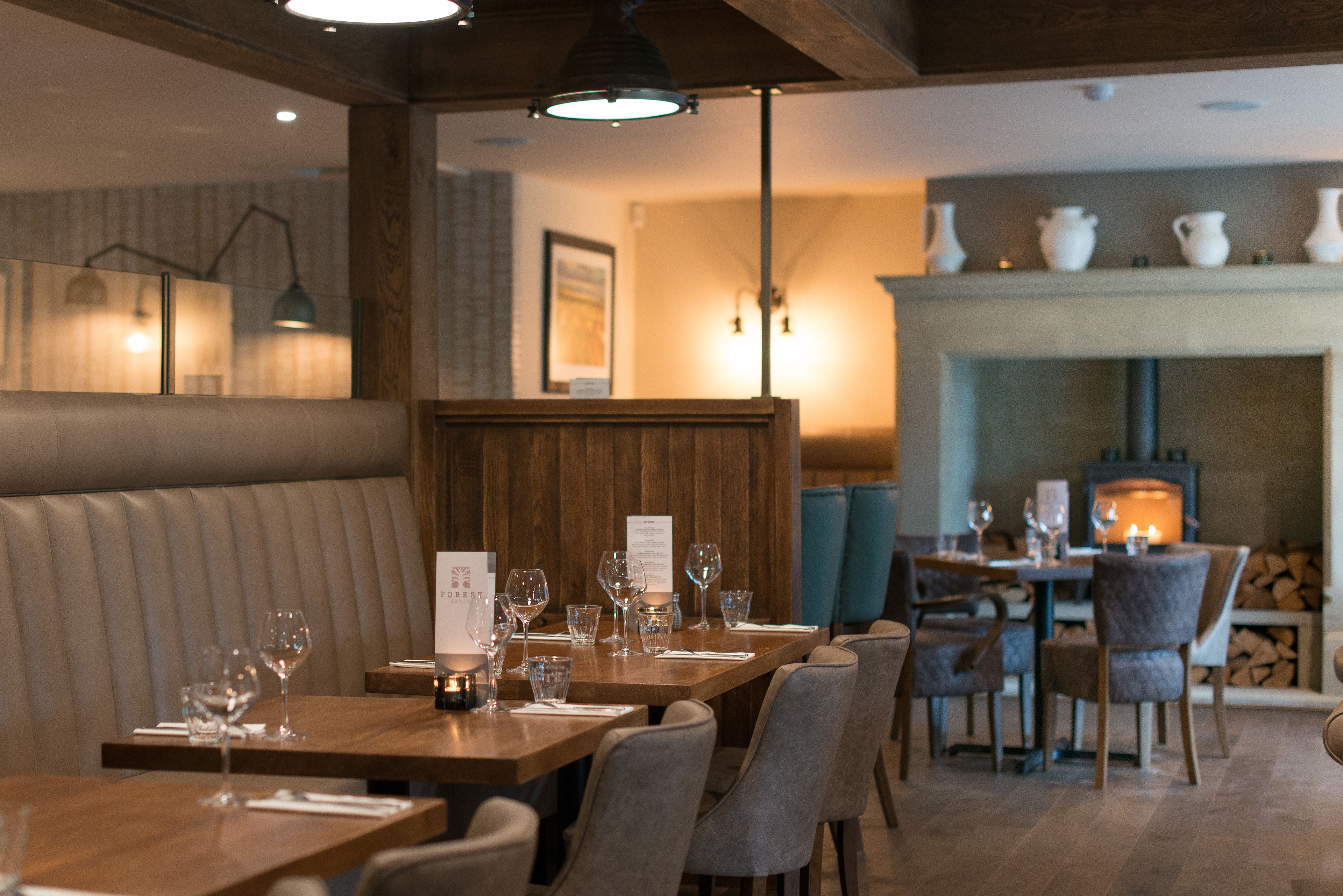A restaurant interior with wooden tables, cushioned booths, and a fireplace.
