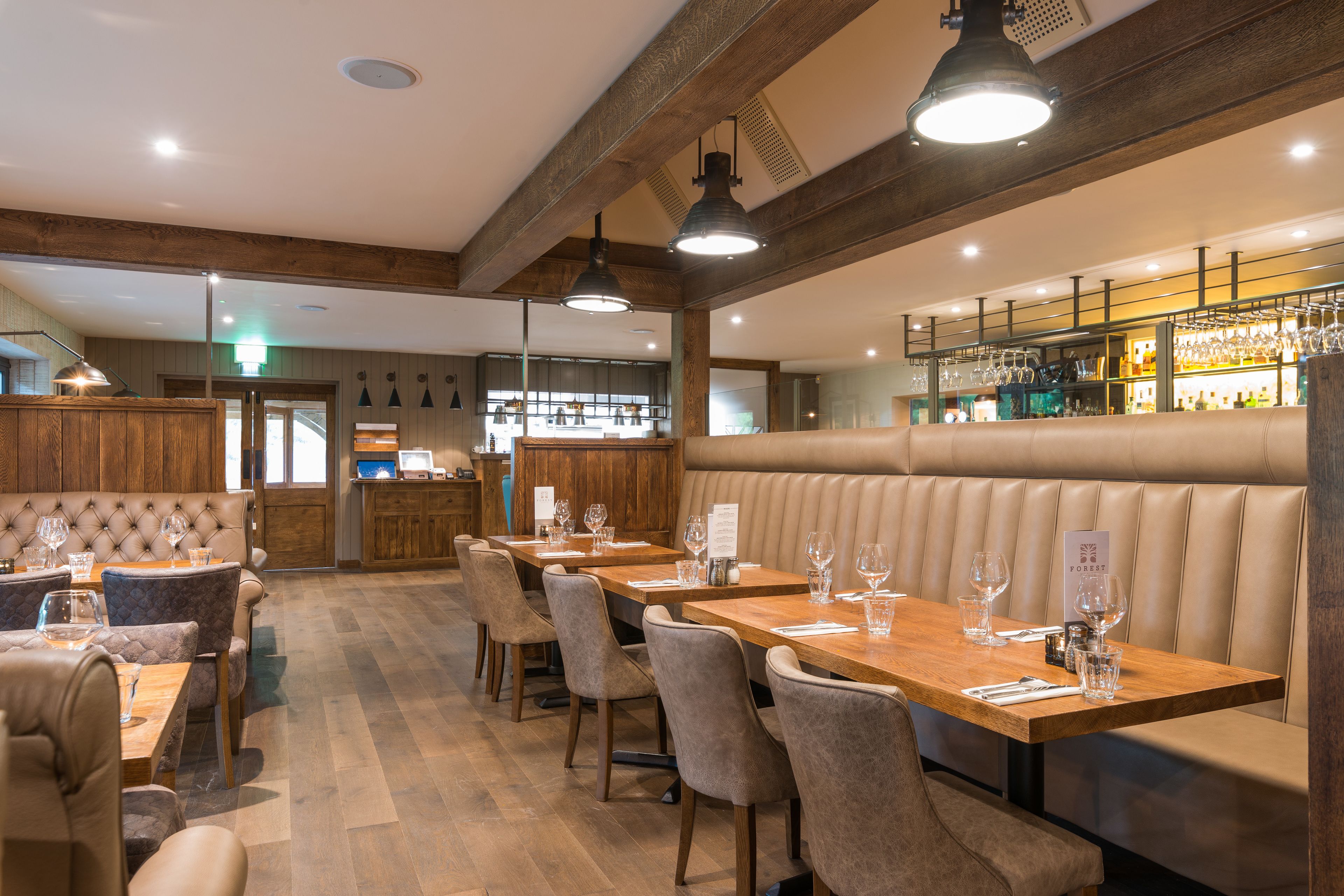 Un restaurant avec des poutres en bois, des banquettes en cuir et un coin bar.