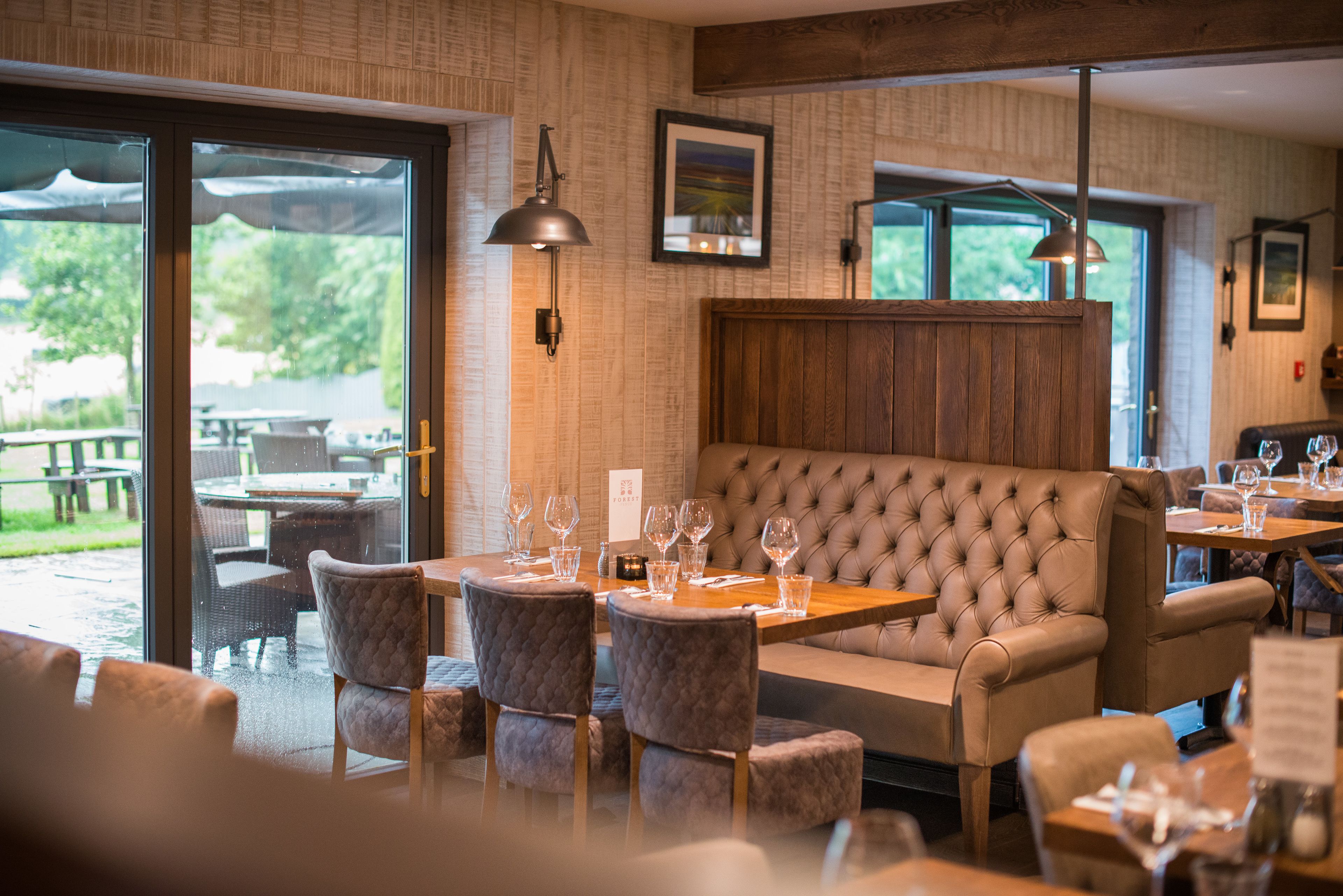 A restaurant with a cozy seating area, large windows, and a view of the outdoors.