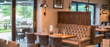 A restaurant with a cozy seating area, large windows, and a view of the outdoors.