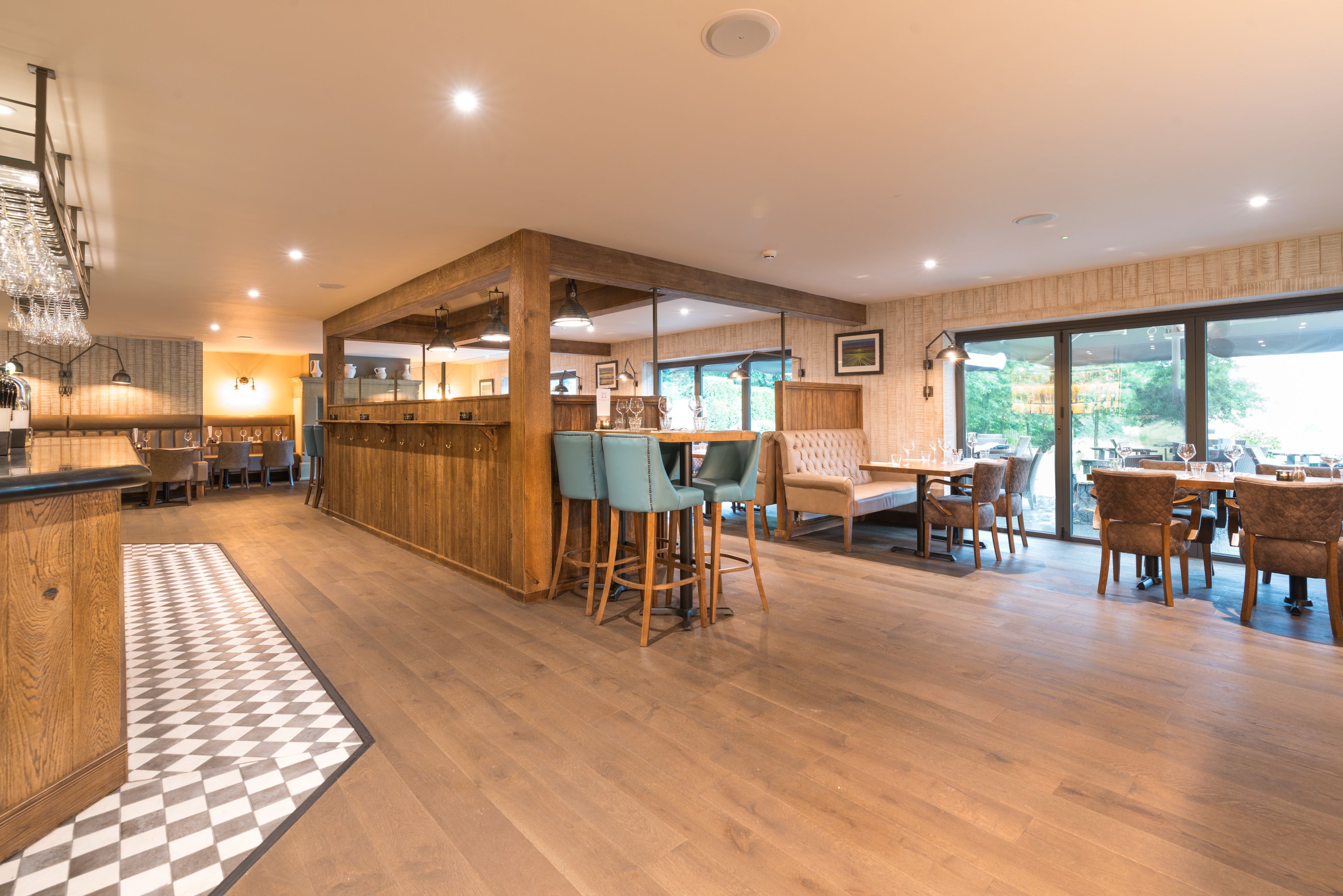 A modern kitchen with wooden accents, a bar area with stools, and a dining area with tables and chairs.