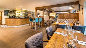 A restaurant with wooden flooring, bar area, and seating arrangements.