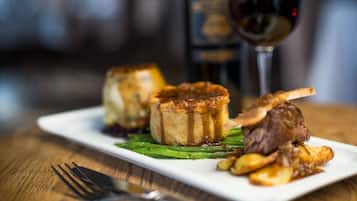 A plate with food and a glass of red wine on a wooden table.