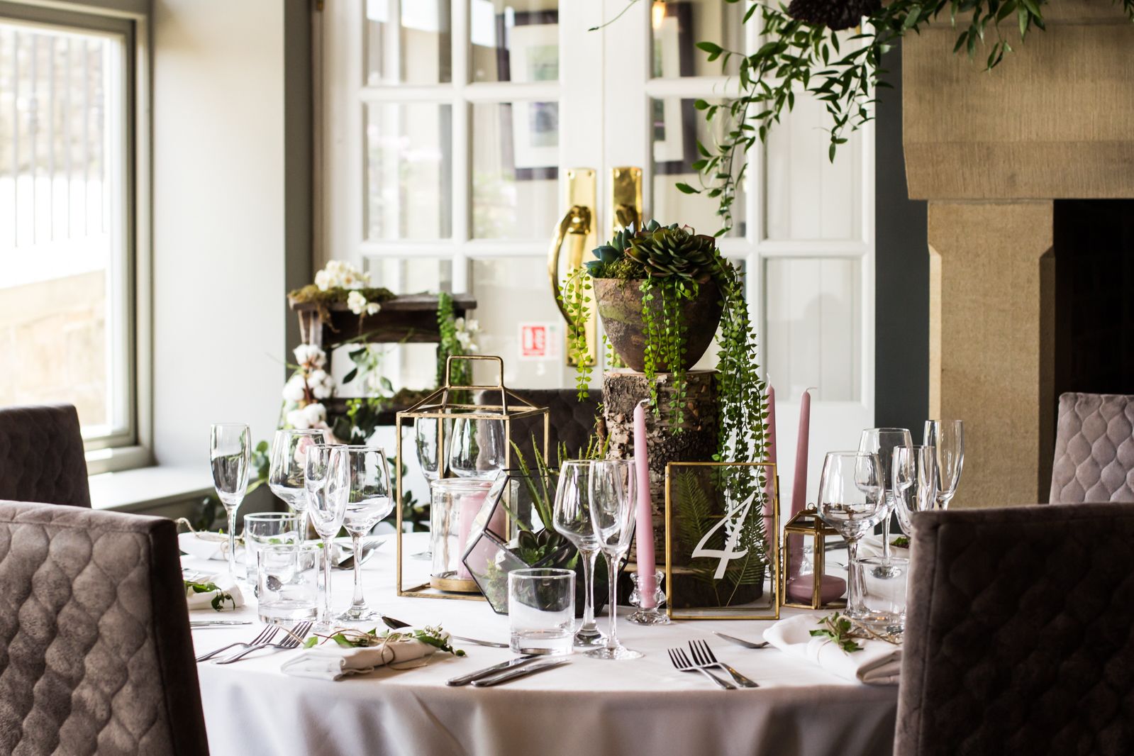 A dining table set with multiple wine glasses, plates, and cutlery, surrounded by chairs.