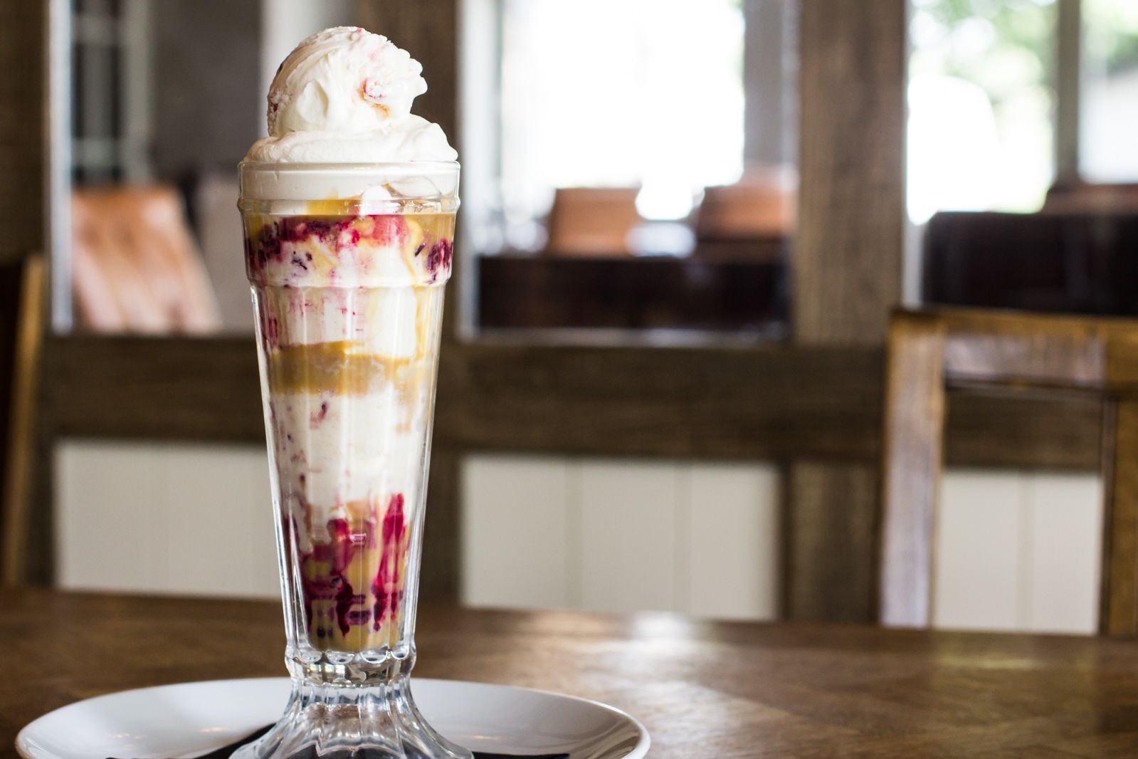 A dessert in a tall glass with layers of fruit and ice cream.