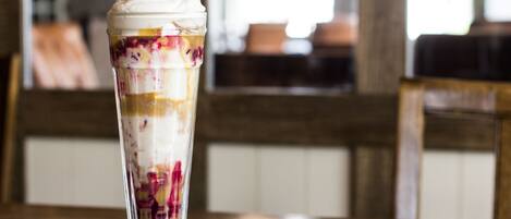 A dessert in a tall glass with layers of fruit and ice cream.