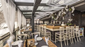 A modern restaurant with a glass ceiling, white orchid decorations, and a wooden bar area. - All Seasons Residence Hotel (Sofia)