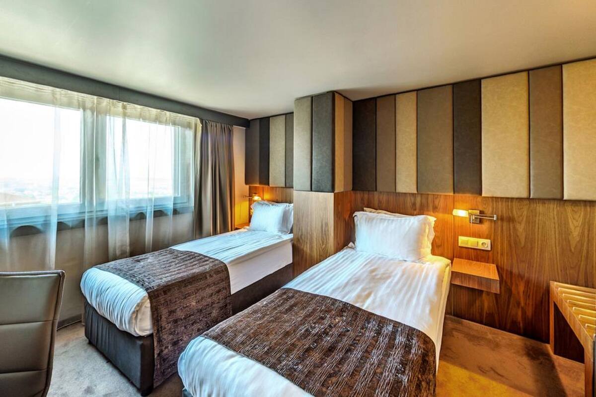 A hotel room with two beds, a desk, and a chair.