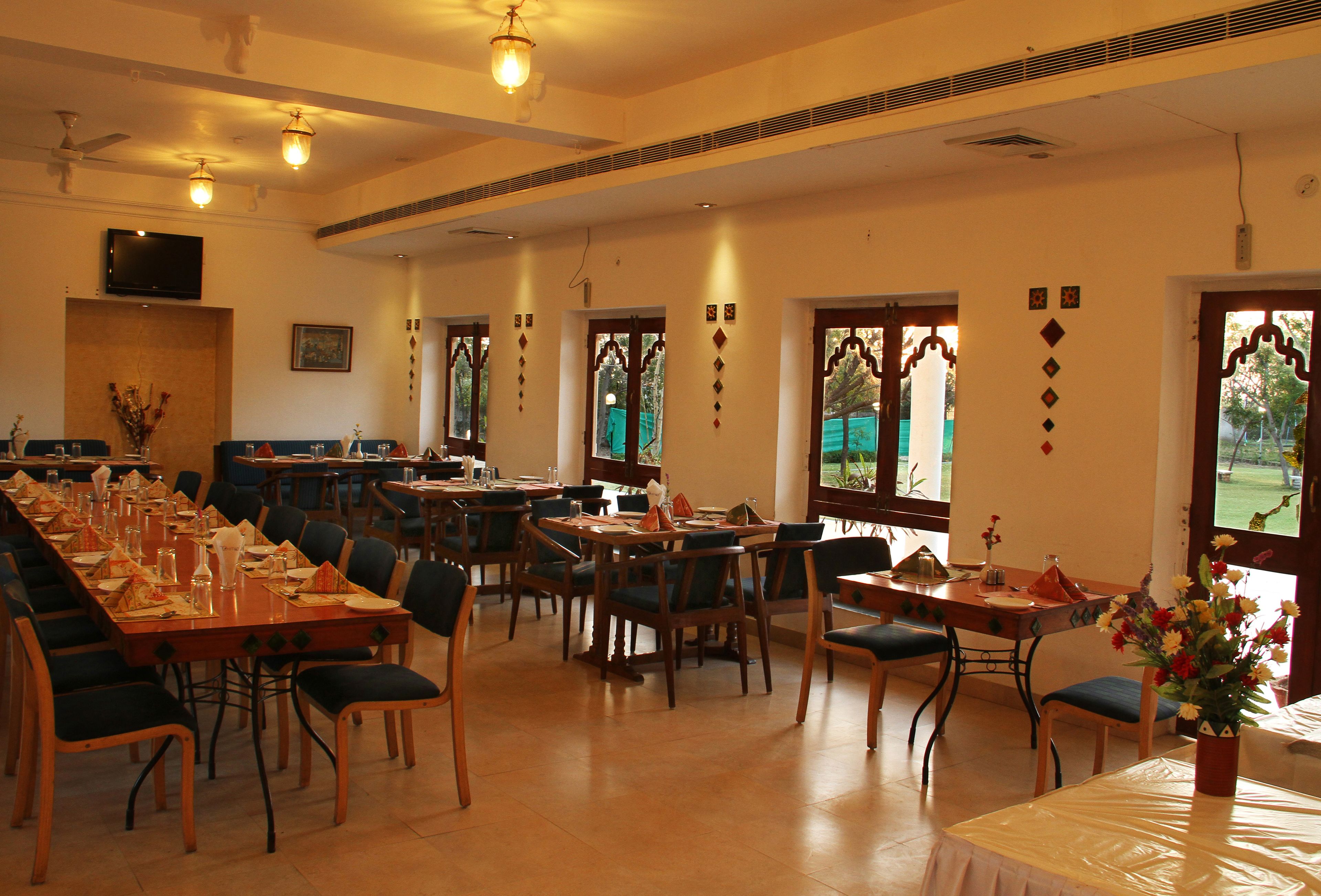 Zona pranzo con diversi tavoli e sedie, una televisione montata a parete e decorazioni murali.