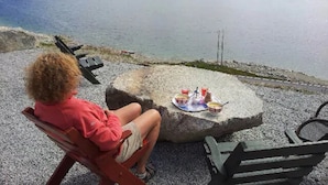Iemand zit aan een tafel met uitzicht op een meer en bergen.